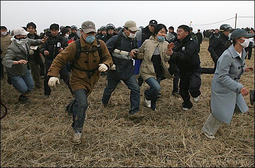 연행작전에 돌입한 경찰들이 흩어지는 활동가들을 붙잡으려 하고 있다. 